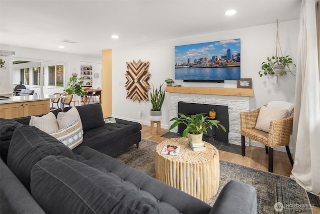 living area with visible vents, recessed lighting, wood finished floors, and a stone fireplace