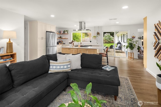 living area with recessed lighting, visible vents, and wood finished floors