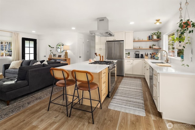 kitchen with open shelves, a sink, stainless steel appliances, island exhaust hood, and a kitchen bar