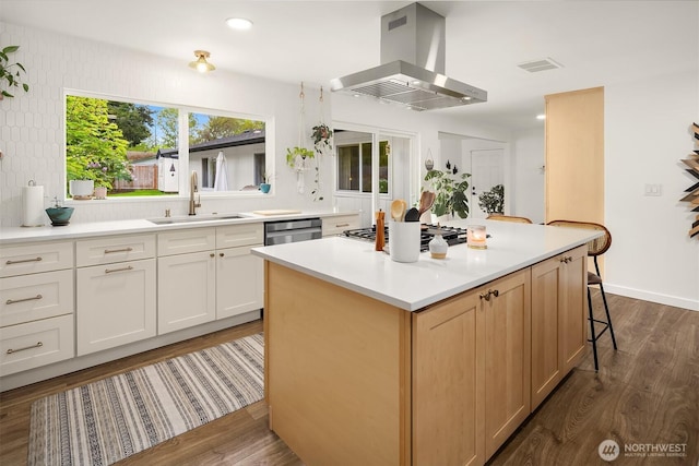 kitchen featuring visible vents, dark wood-style flooring, island exhaust hood, a sink, and stainless steel gas stovetop