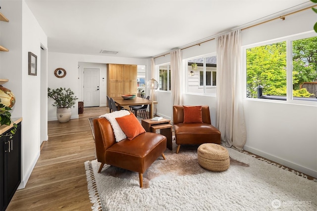living area featuring light wood-type flooring, baseboards, and visible vents