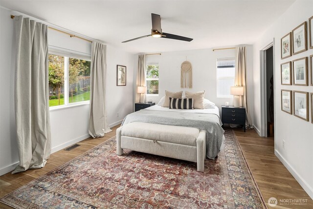 bedroom with a ceiling fan, baseboards, visible vents, and wood finished floors