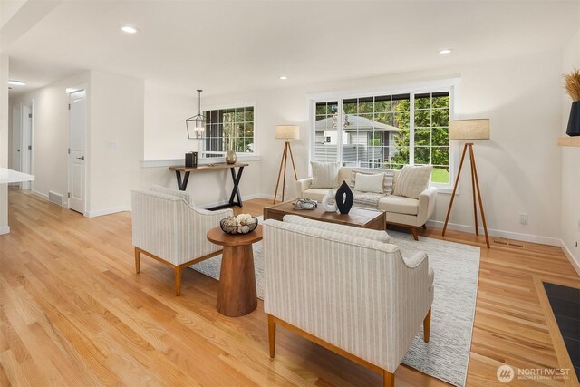 living area with baseboards, visible vents, plenty of natural light, and light wood finished floors