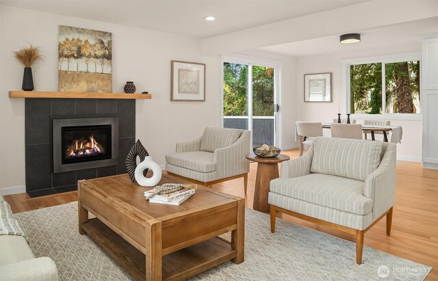 living room featuring recessed lighting, a tile fireplace, a healthy amount of sunlight, and light wood-style floors