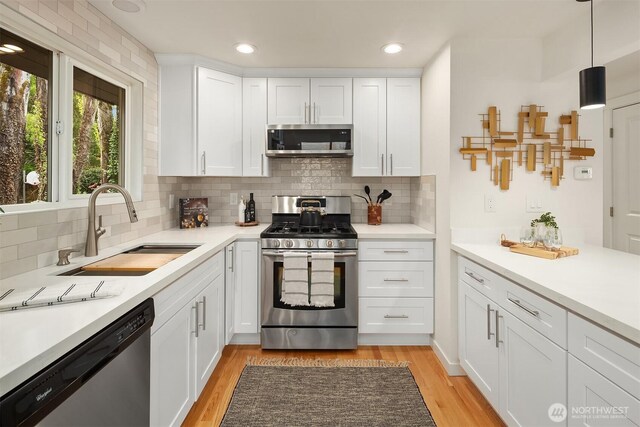 kitchen featuring light countertops, a sink, appliances with stainless steel finishes, and tasteful backsplash