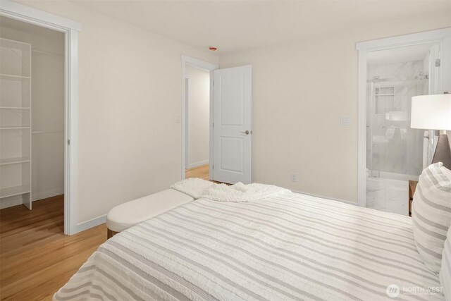 bedroom featuring a walk in closet, baseboards, a closet, connected bathroom, and light wood-style flooring