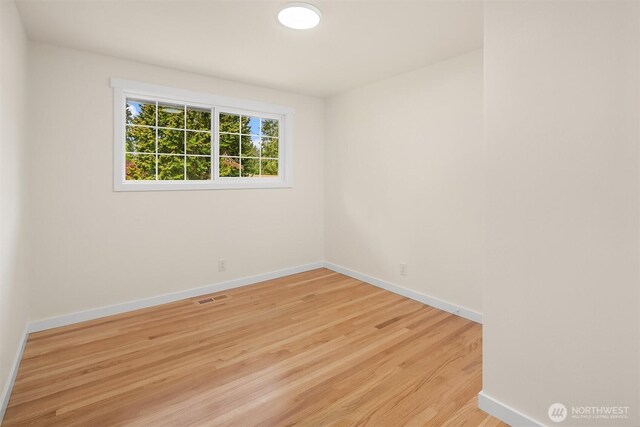 empty room featuring baseboards, visible vents, and light wood-style flooring