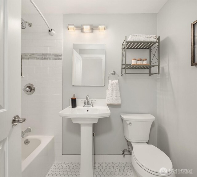 full bath featuring baseboards, tile patterned flooring, toilet, and shower / washtub combination