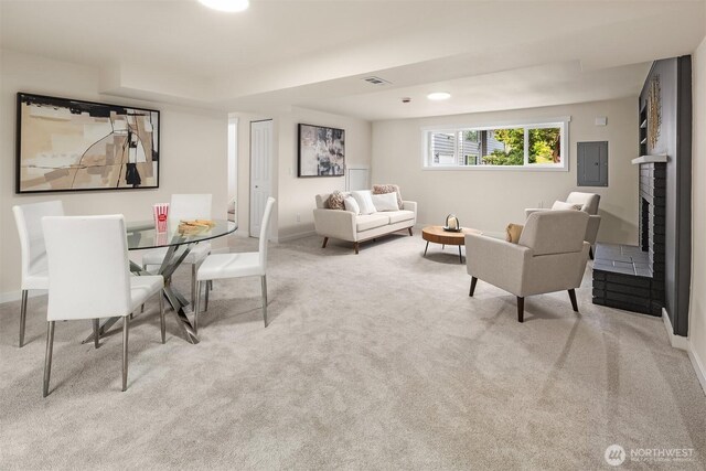 carpeted living room featuring visible vents, baseboards, a brick fireplace, and electric panel
