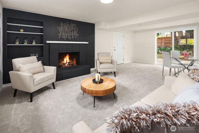 living room with carpet floors, baseboards, built in shelves, and a fireplace