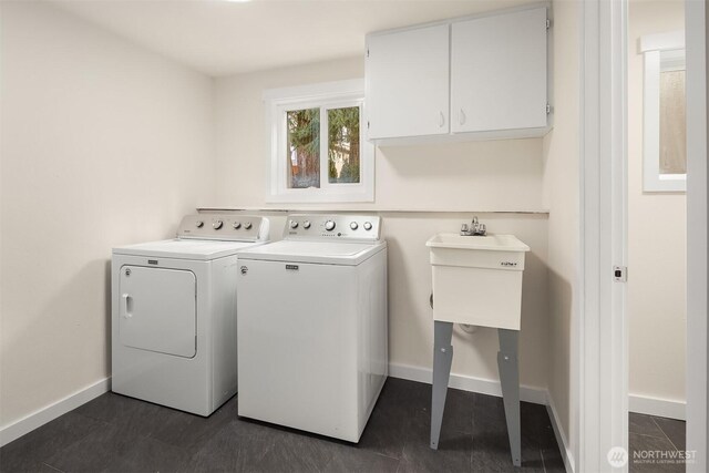 clothes washing area with baseboards, washing machine and dryer, and cabinet space