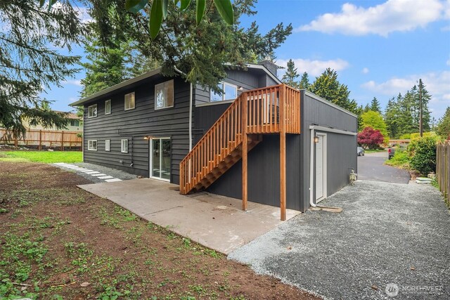 back of house featuring stairway, fence, a wooden deck, and a patio area