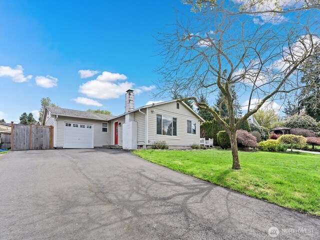 single story home with a garage, fence, a front yard, a chimney, and driveway