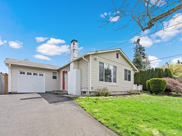 ranch-style home featuring an attached garage, a front lawn, aphalt driveway, and a chimney