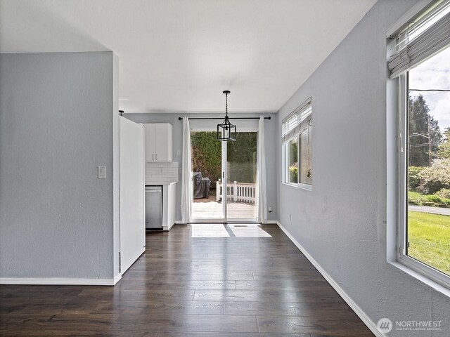 unfurnished dining area with baseboards, dark wood finished floors, and a textured wall