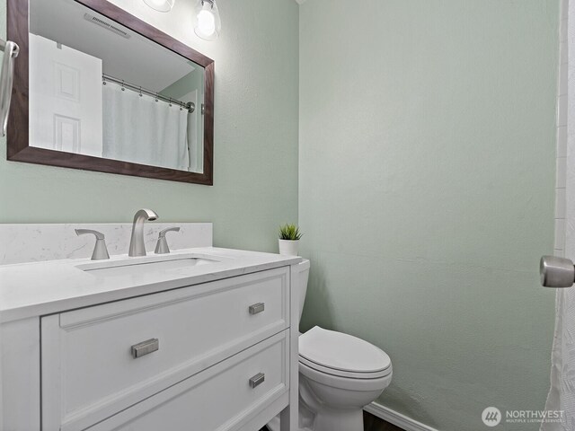 bathroom featuring toilet, a shower with shower curtain, and vanity
