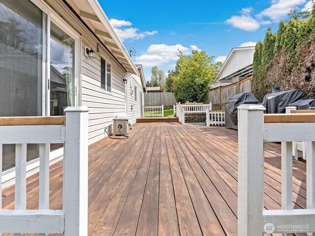 wooden terrace with a fenced backyard and area for grilling