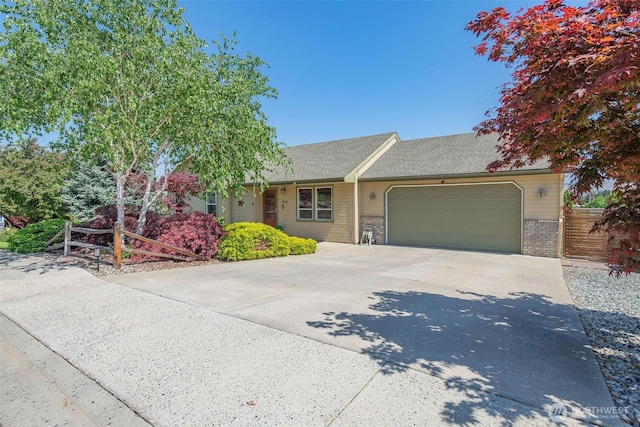 ranch-style house featuring fence, an attached garage, brick siding, and driveway