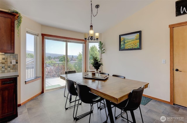 dining space featuring an inviting chandelier, lofted ceiling, and baseboards