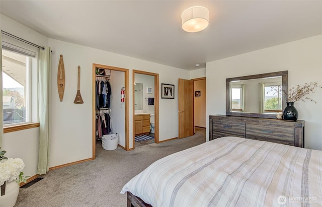 carpeted bedroom featuring a closet, ensuite bathroom, baseboards, and a spacious closet