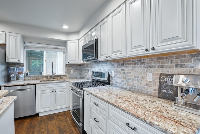 kitchen with appliances with stainless steel finishes, a sink, white cabinets, light stone counters, and recessed lighting