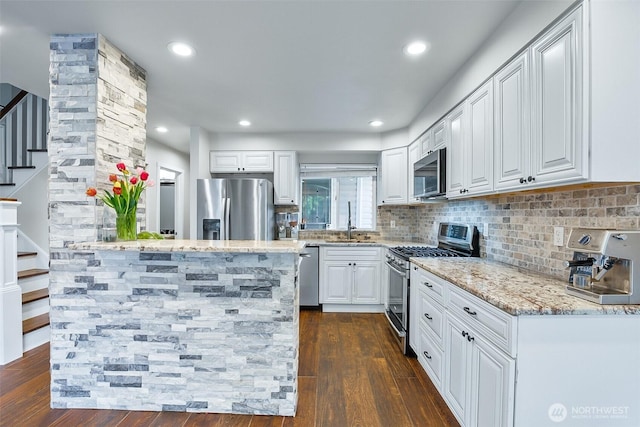 kitchen featuring appliances with stainless steel finishes, light stone counters, backsplash, dark wood finished floors, and recessed lighting