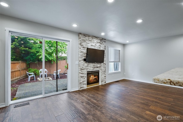 unfurnished living room featuring wood finished floors, healthy amount of natural light, baseboards, recessed lighting, and a stone fireplace