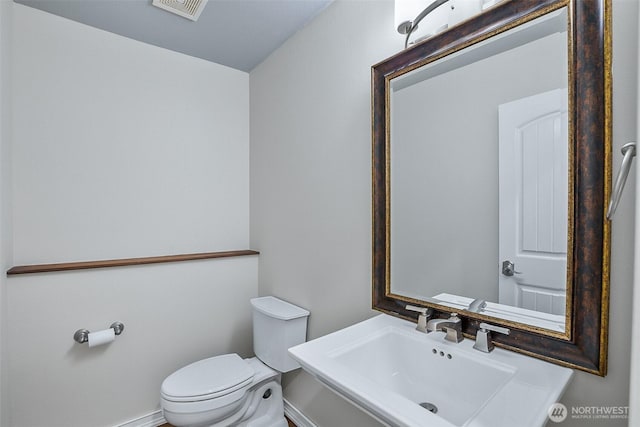 bathroom with a sink, toilet, and baseboards