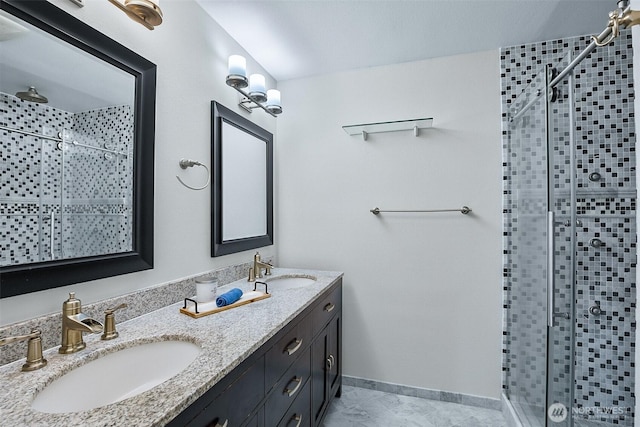 full bath featuring a stall shower, double vanity, and baseboards