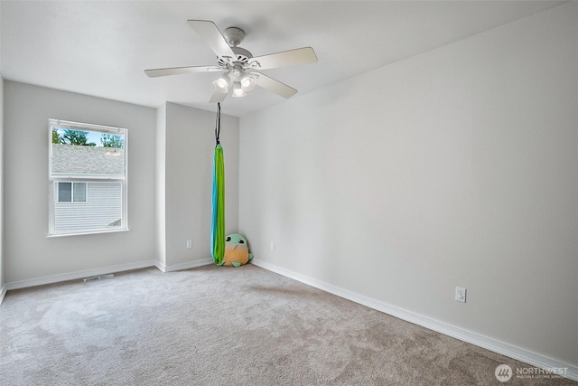 carpeted empty room featuring a ceiling fan and baseboards
