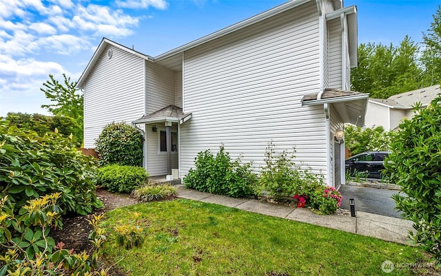 rear view of property featuring a garage and a lawn