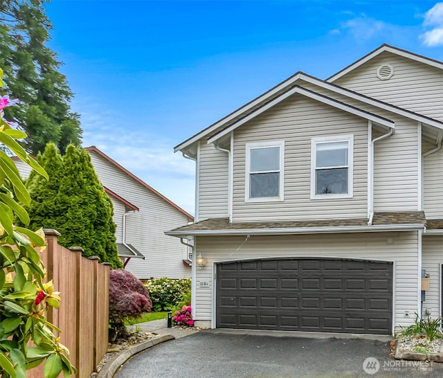 view of front of house featuring an attached garage, asphalt driveway, and fence