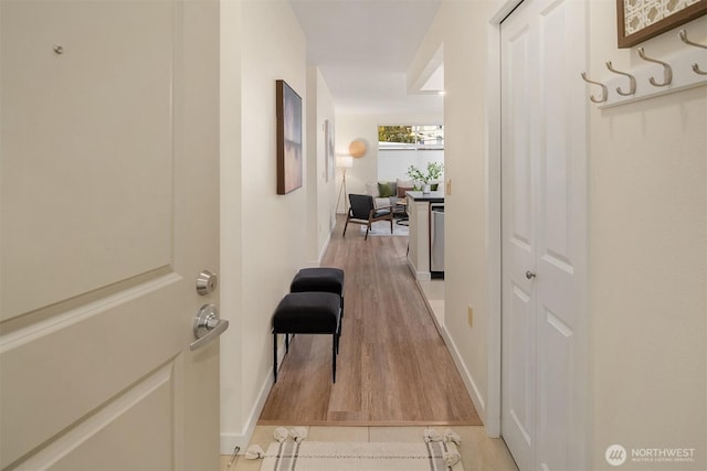 hall with baseboards and light wood-style floors