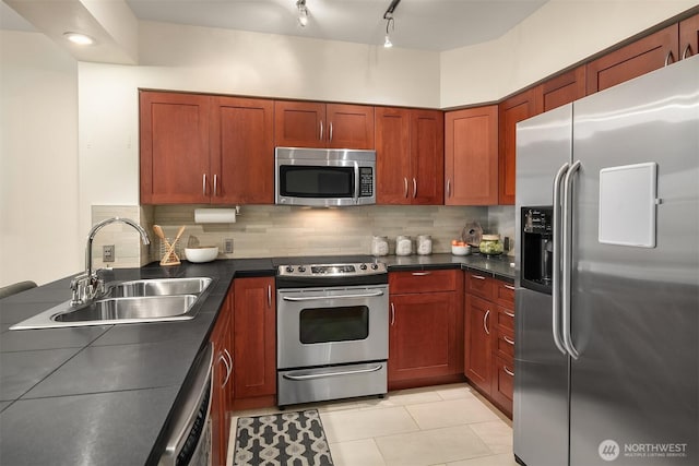 kitchen with a sink, tasteful backsplash, dark countertops, and stainless steel appliances