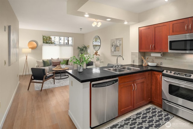 kitchen with a peninsula, dark countertops, recessed lighting, a sink, and stainless steel appliances