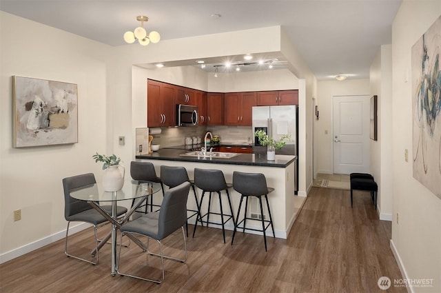 kitchen with baseboards, dark wood-style floors, dark countertops, and stainless steel appliances