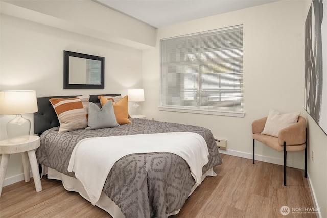 bedroom featuring baseboards, a baseboard heating unit, and light wood-type flooring