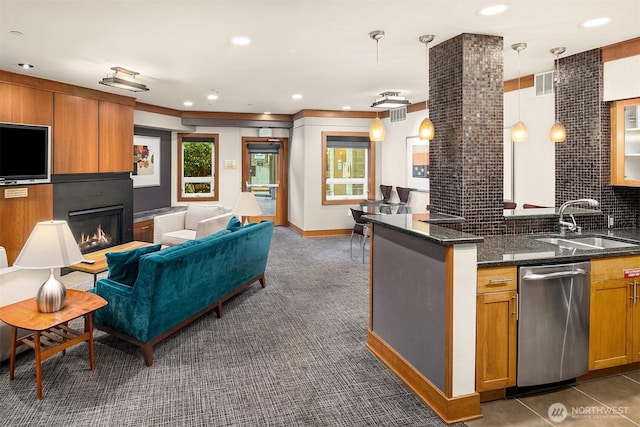 kitchen with stainless steel dishwasher, visible vents, dark colored carpet, brown cabinets, and a sink