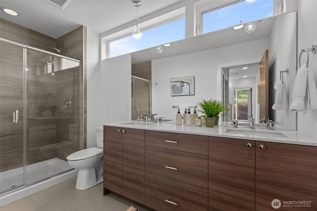 bathroom with a sink, toilet, double vanity, tile patterned floors, and a stall shower