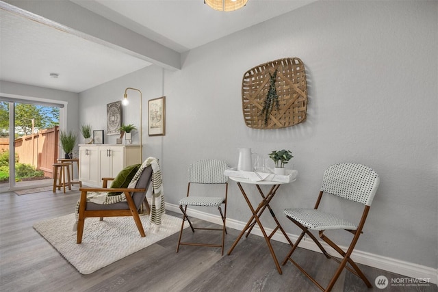 sitting room with wood finished floors, beamed ceiling, and baseboards