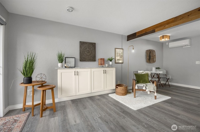 living area featuring a wall mounted air conditioner, wood finished floors, baseboards, and beamed ceiling