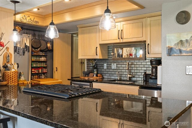kitchen with hanging light fixtures, tasteful backsplash, a sink, cooktop, and ornamental molding