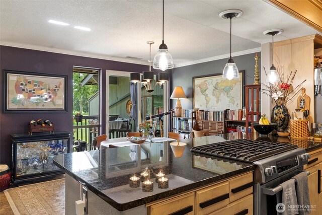 kitchen featuring crown molding, hanging light fixtures, stainless steel gas range oven, dark stone countertops, and visible vents