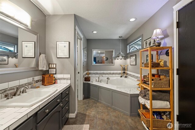 bathroom featuring recessed lighting, a garden tub, and vanity