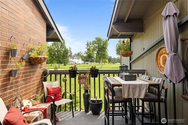 deck with view of golf course, outdoor dining area, and a yard