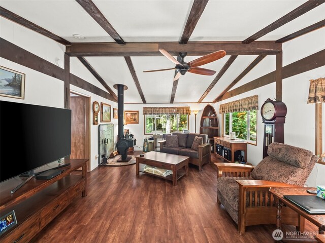 living area with ceiling fan, lofted ceiling with beams, wood finished floors, and a wood stove