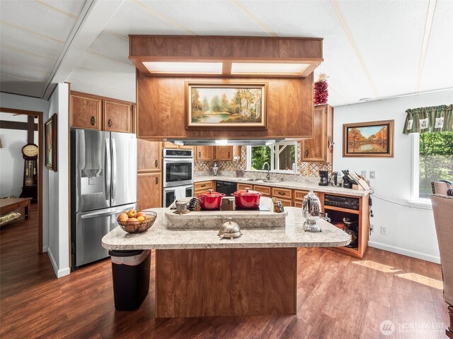 kitchen with appliances with stainless steel finishes, plenty of natural light, decorative backsplash, and brown cabinets