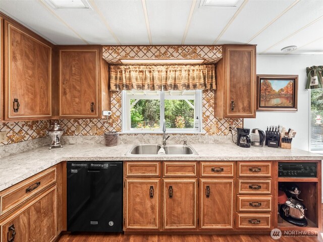 kitchen featuring brown cabinetry, backsplash, a sink, light countertops, and black dishwasher