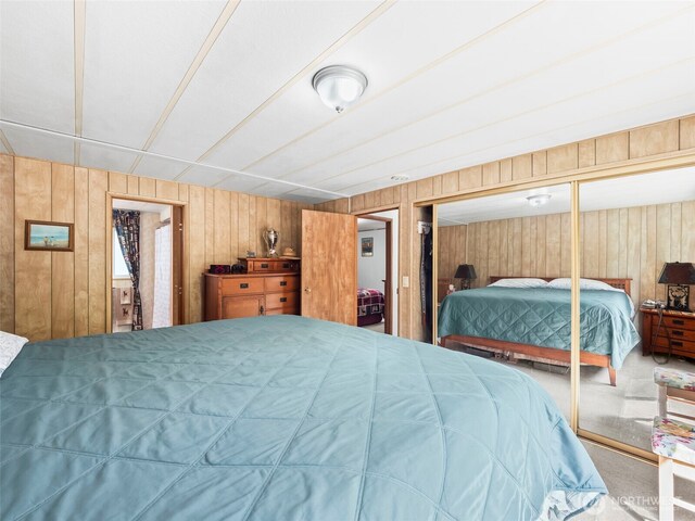 bedroom featuring wood walls, carpet, and a closet