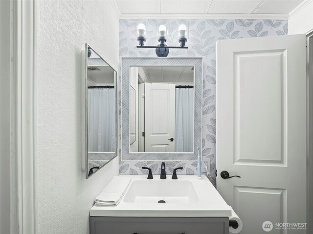 full bath featuring a textured wall and vanity